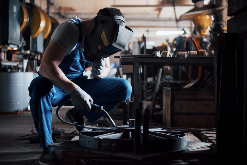 Portrait of a young worker at a large metalworking plant. The welder engineer works in a protective