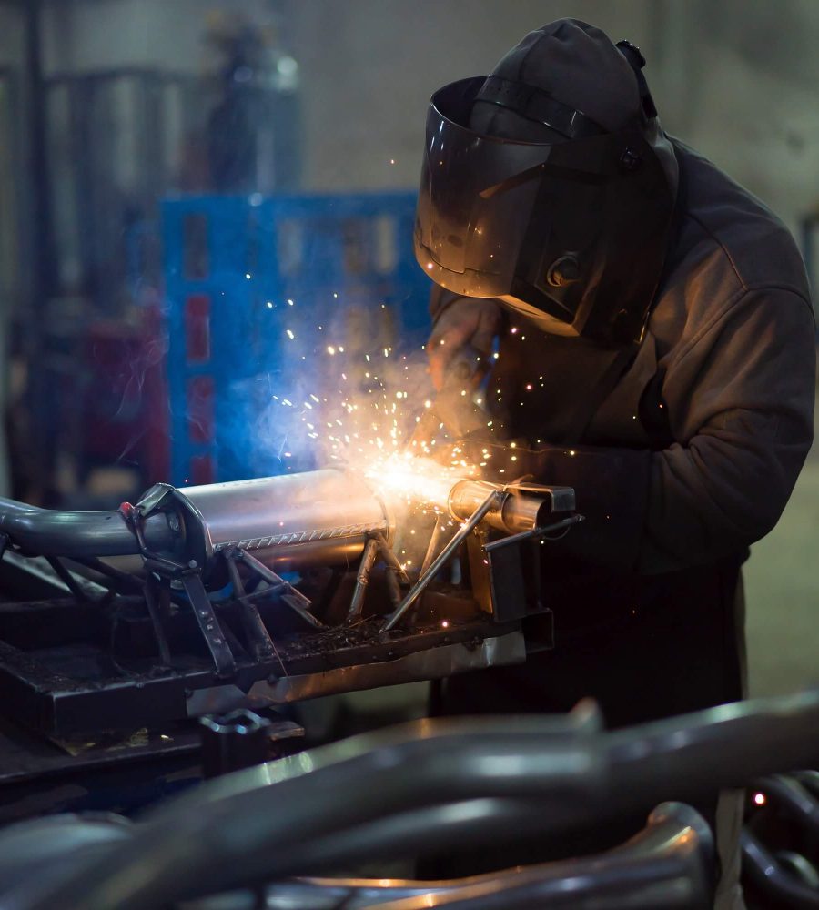 worker-welding-exhaust-pipes-pieces-together