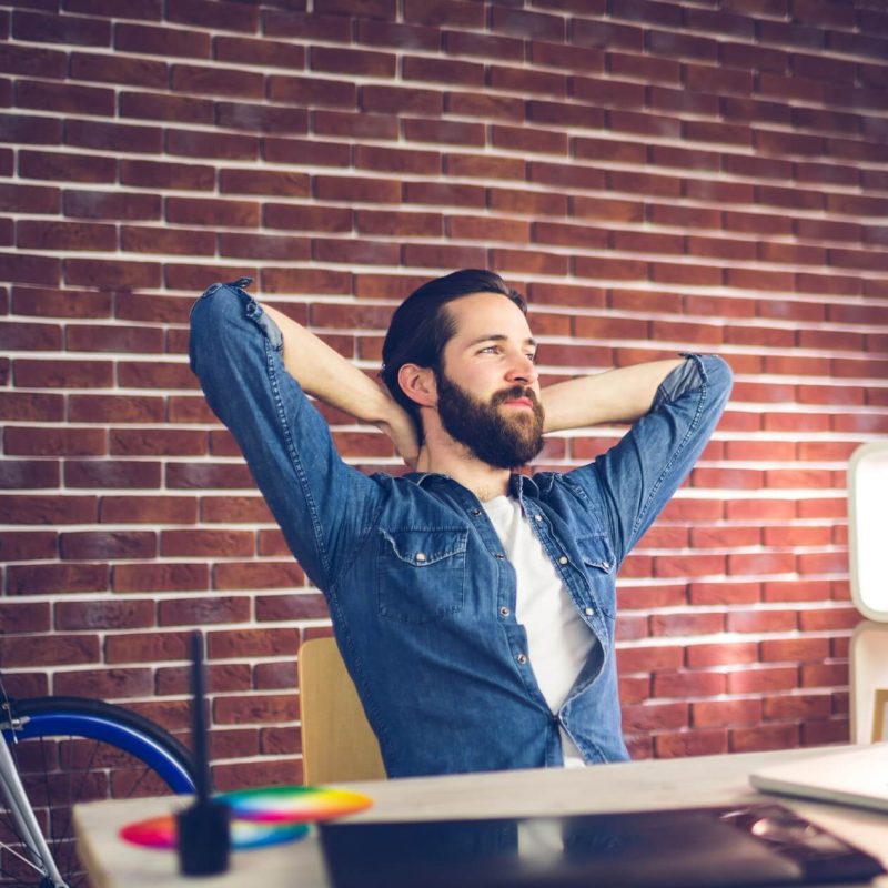 thoughtful-businessman-with-hands-behind-back-relaxing-in-creative-office